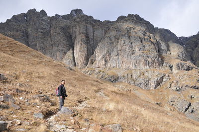 Man walking on rocky mountain against sky