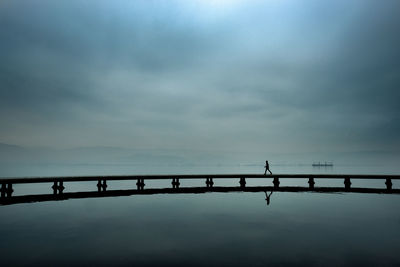 Side view of man walking on pier in lake