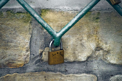 Love padlock hanging on fence by wall