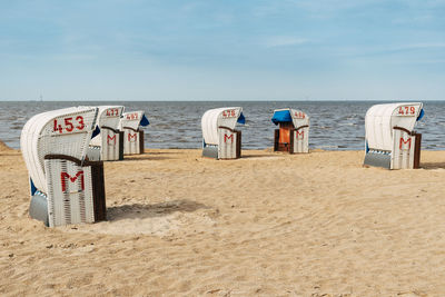 Hooded chairs on beach against sky