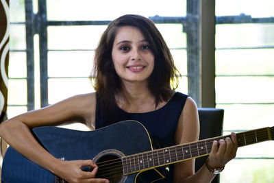 Portrait of young woman playing guitar