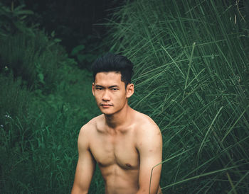 Portrait of shirtless young man standing on land