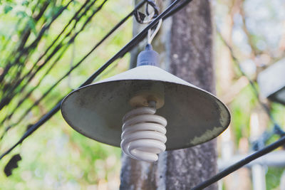 Low angle view of light bulb hanging against pole