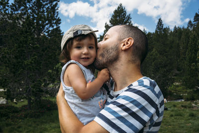 Spain, father hugging and kissing his little daughter in nature