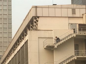Low angle view of man standing on staircase against building