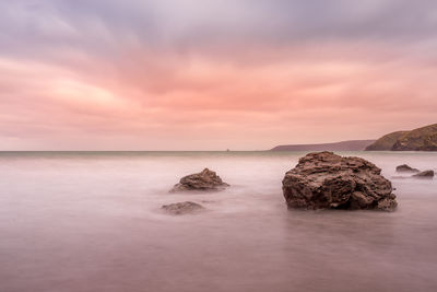 Rocks on sea against sky during sunset