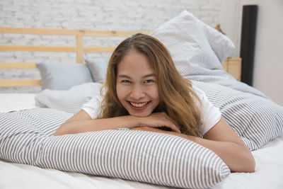 Portrait of smiling young woman lying on bed