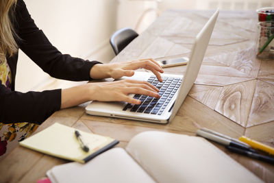 Cropped image of businesswoman using laptop at desk in office