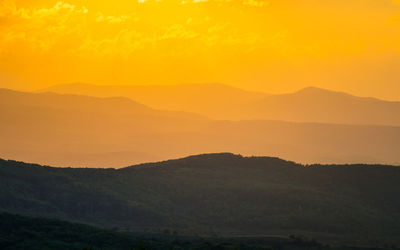 Scenic view of silhouette mountains against orange sky