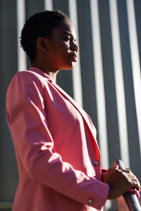 Low angle view of businesswoman looking away while standing against wall