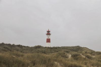 Lighthouse by street amidst buildings against sky