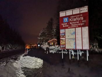 Information sign on snow against sky at night during winter