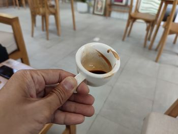 Midsection of person holding coffee cup on table