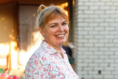 Portrait of young woman standing against brick wall