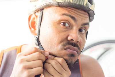 Close-up portrait of man adjusting helmet