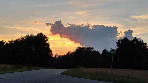 Scenic view of road against cloudy sky at sunset