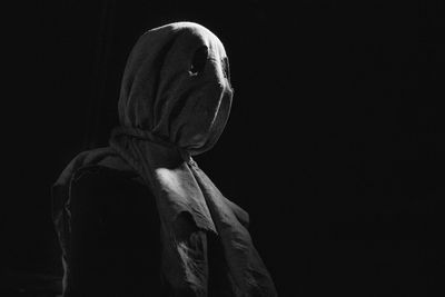 Person in mask against black background