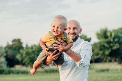 Father carrying cute baby son while standing in park