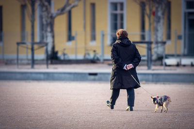 Woman with dog walking on city street