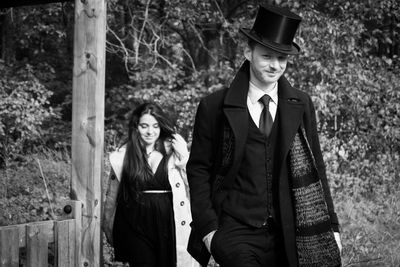 Portrait of young couple standing against trees