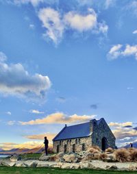 Man outside house on field against sky