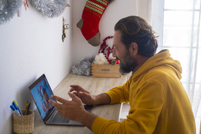 Side view of young man using mobile phone at home