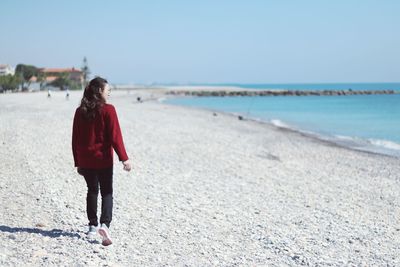 Rear view of woman on beach against clear sky