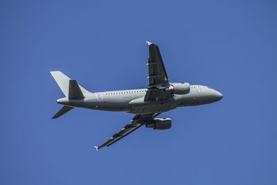 Low angle view of airplane flying against clear blue sky