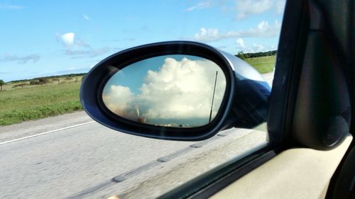 Reflection of clouds in side-view mirror