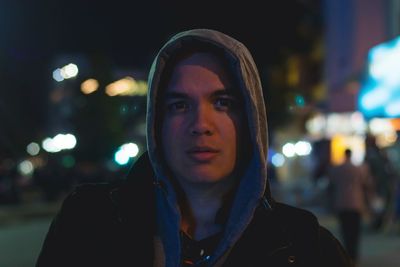 Portrait of handsome man wearing hooded jacket at night