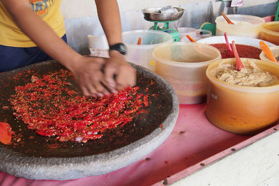 Midsection of man grinding red chili pepper