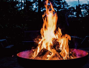 Close-up of burning fire pit on field at dusk