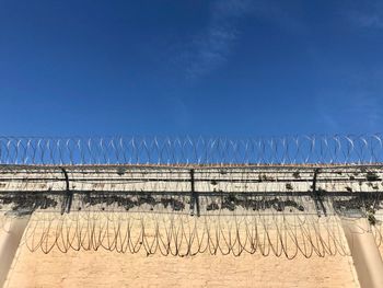 Low angle view of razor wire against blue sky