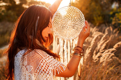 Asian girl holding dream catcher at sunset in field