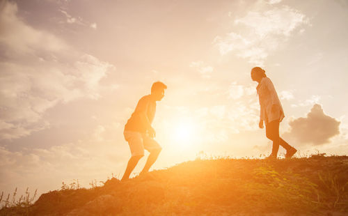 Friends standing on land against sky during sunset