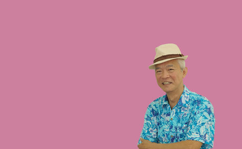 Portrait of smiling young woman standing against pink background