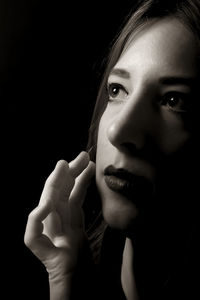 Close-up portrait of young woman against black background