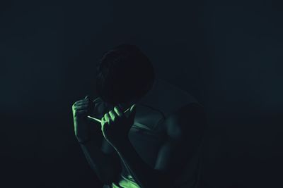 Midsection of man holding illuminated light in darkroom