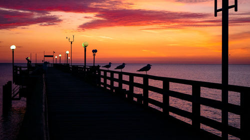 Pier over sea against sky during sunset