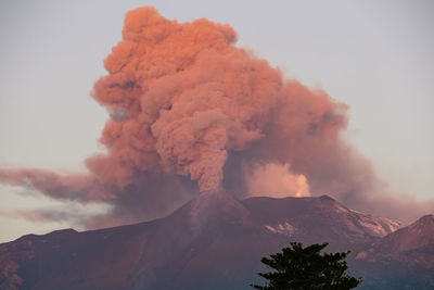 Low angle view of the cityscape against the sky during the strombolian eruption of etna