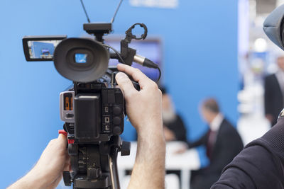 Cropped hands of male tv reporter holding television camera