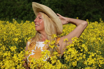 Portrait of young woman with yellow flowers in field