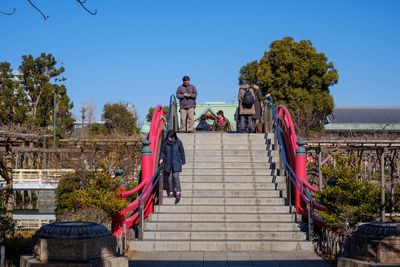 People on staircase against clear blue sky