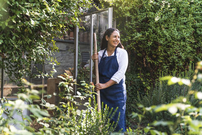 Smiling mature woman looking away while standing in back yard