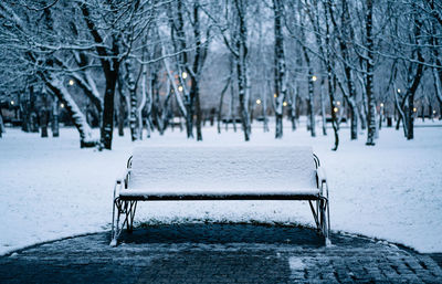 Empty snow covered bench in the park in a winter morning