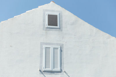 Detail of a white house and white windows with a blue sky