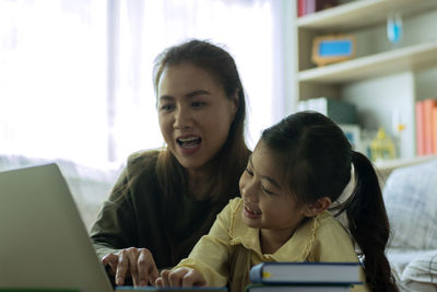 Portrait of mother and daughter sitting on laptop