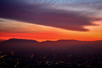 Scenic view of illuminated city against romantic sky at sunset