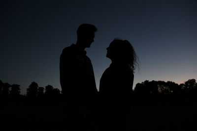 Silhouette couple standing against clear sky at night