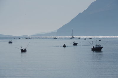 People fishing in sea against sky